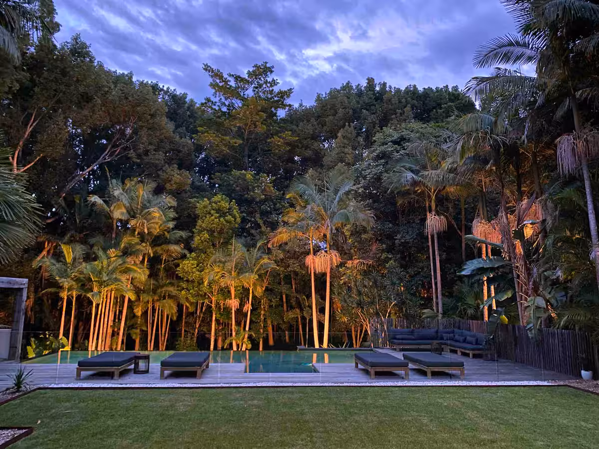 Two Acres at dusk, palms lit above the pool